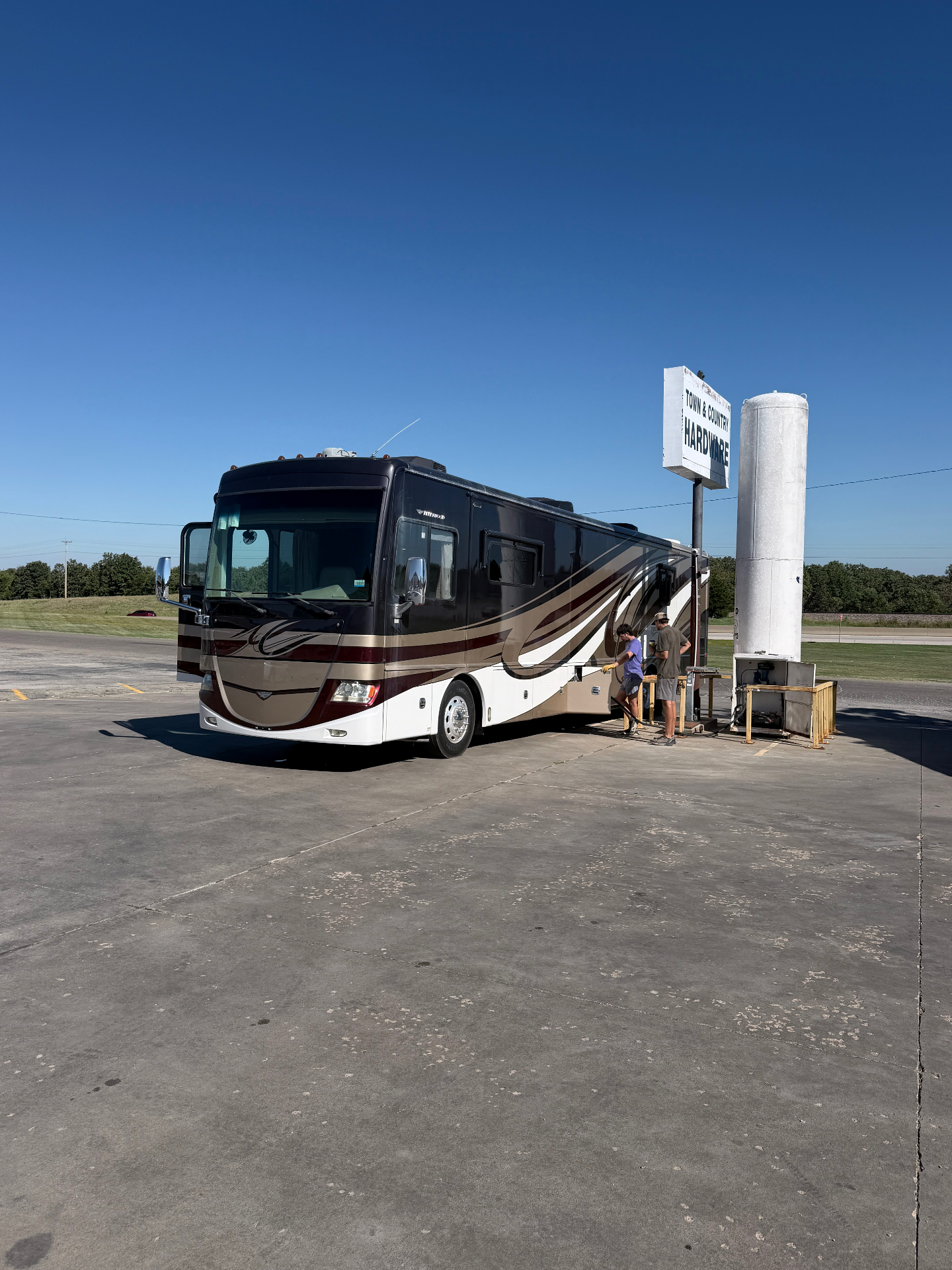 Large motor coach pulled up beside the Town & Country Hardware propane refill station