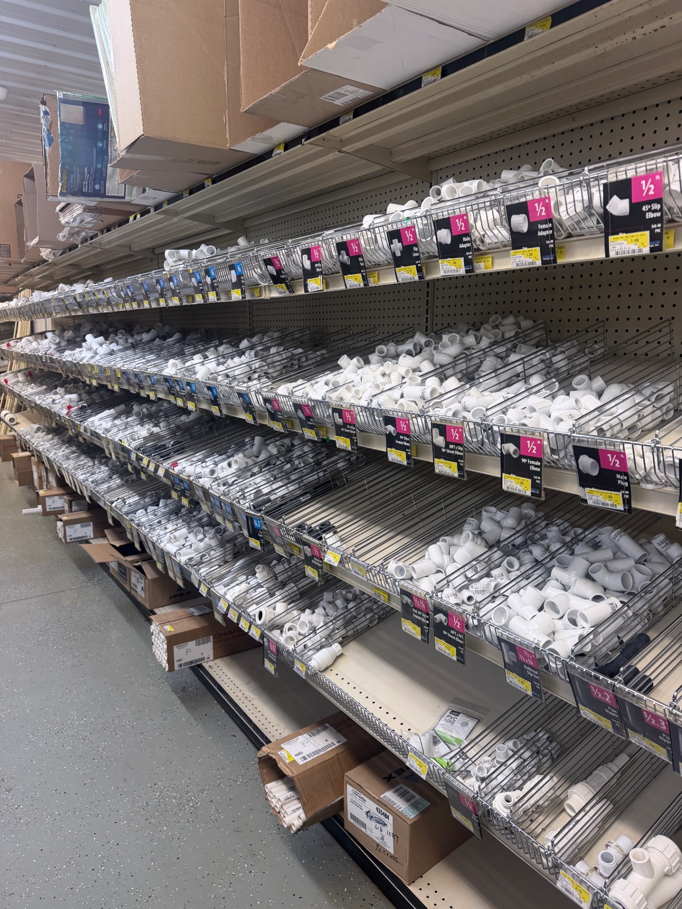 Bins of white PVC fittings and connectors organized by size